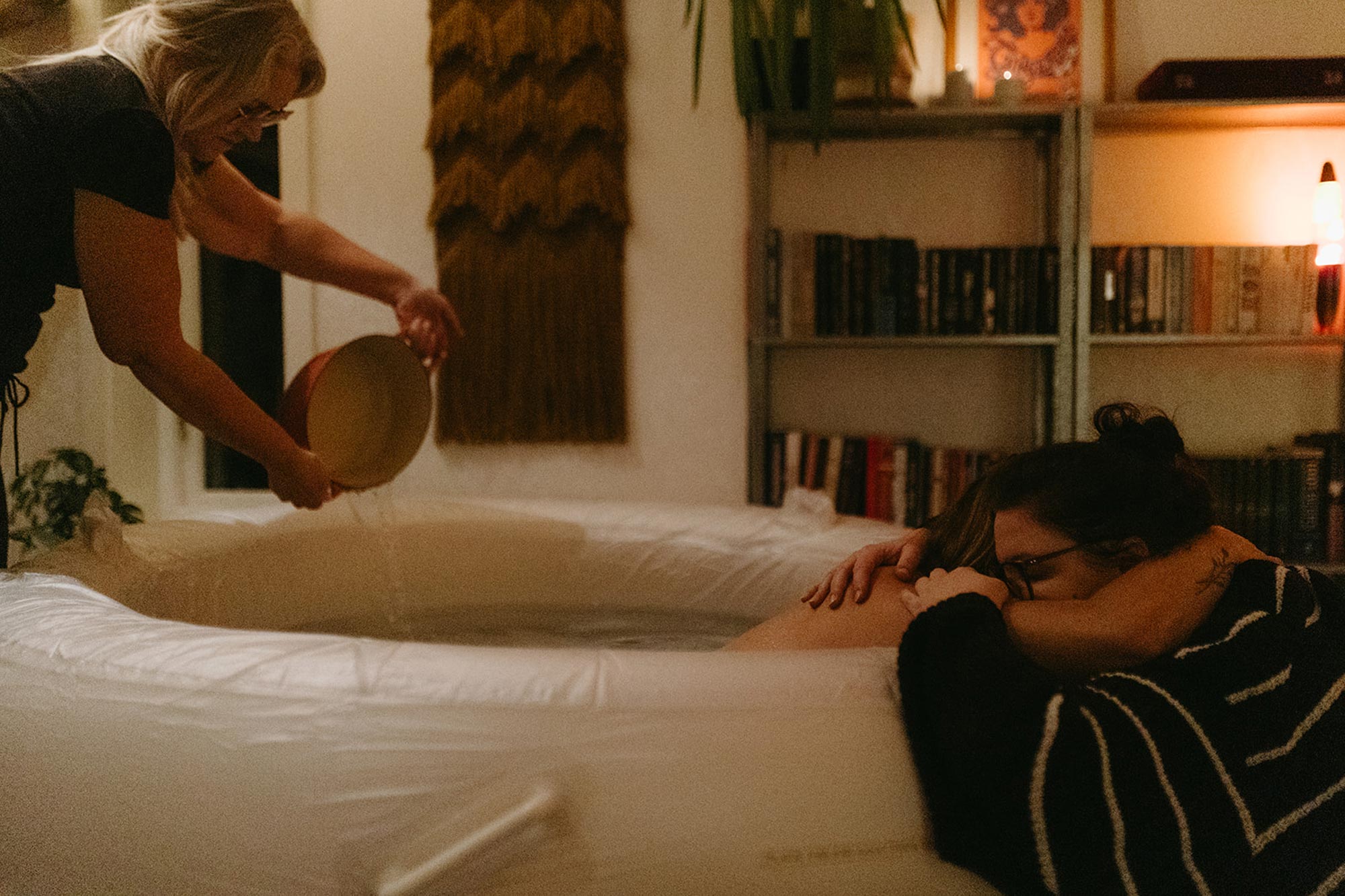 Den födande ligger i en födselpool och håller om sin partner