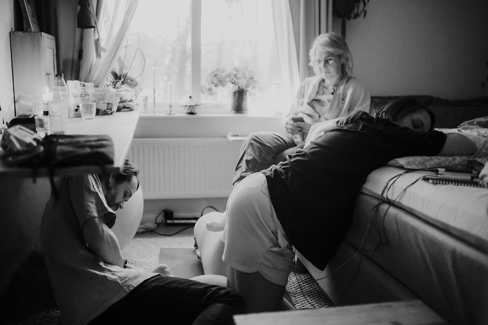 Den födande står på knä och lutar sig mot sängkanten av sängen