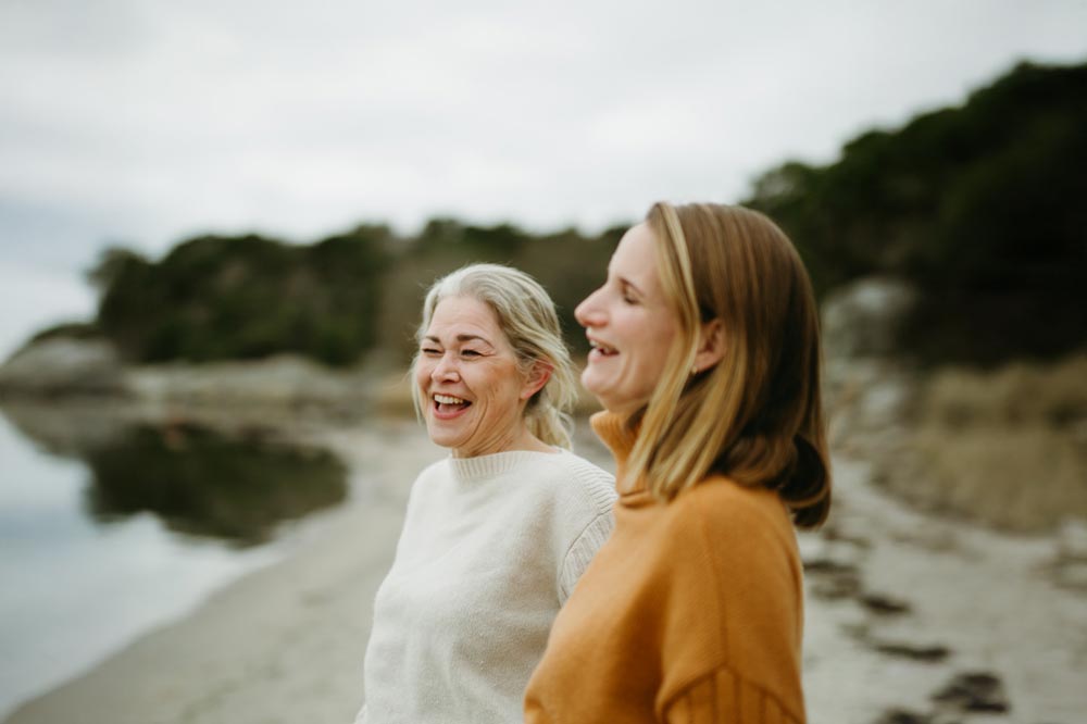 Johanna och Nadia står på en strand och skrattar tillsammans