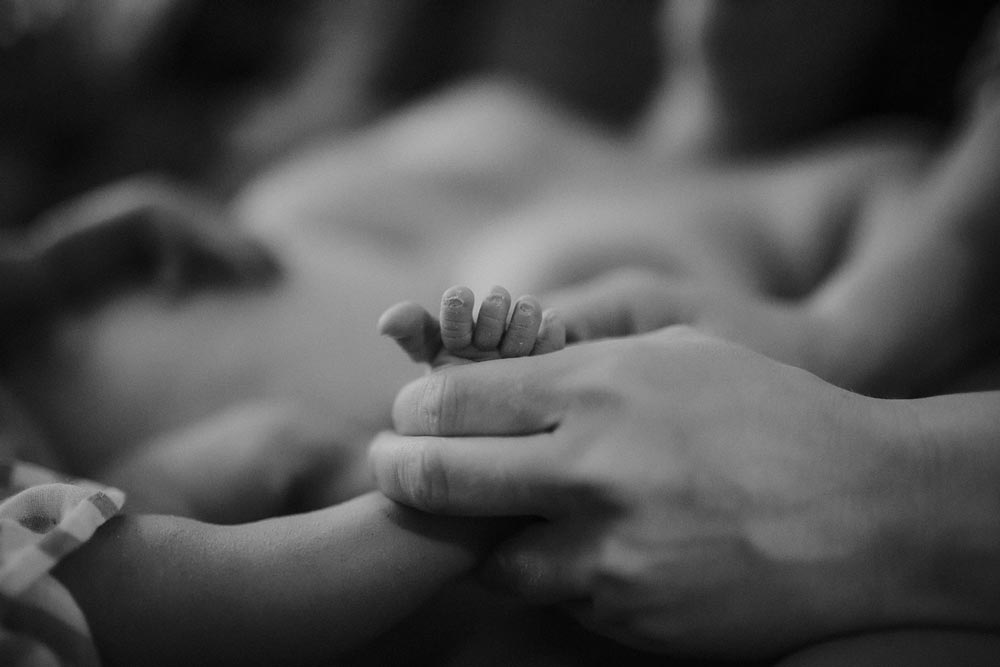 Partner håller i foten på sitt nyfödda barn