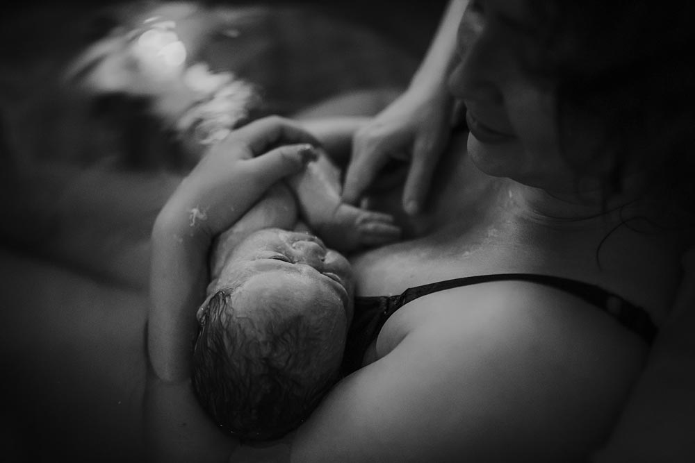 Nyfödd som ligger hud mot hud hos sin mamma i en födelsepool